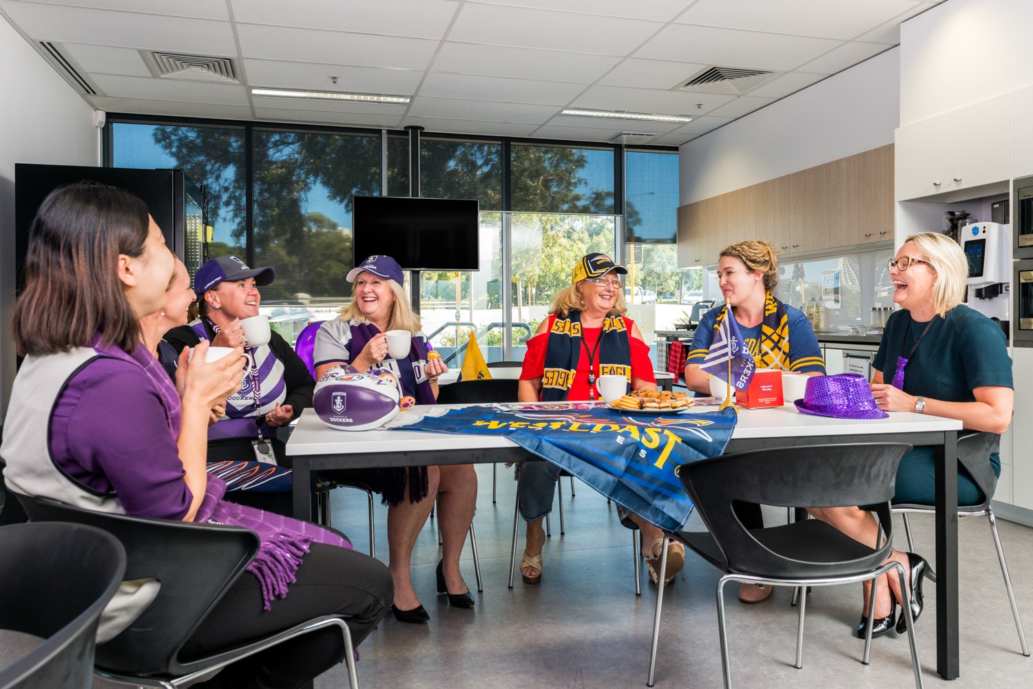 Colleagues gathered around a table in a football-themed office
