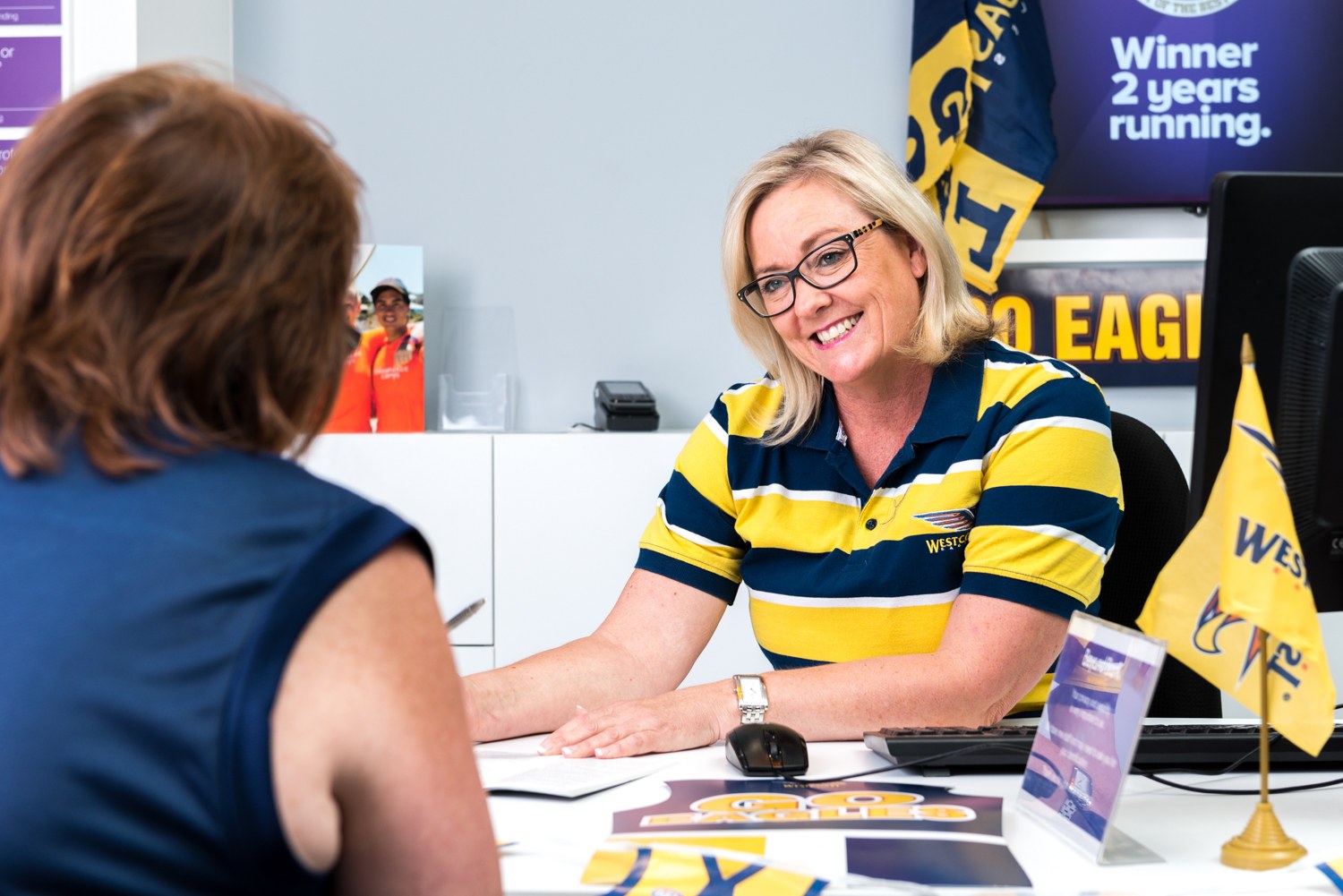 Beyond Bank staff member speaking with a customer in a football-themed branch