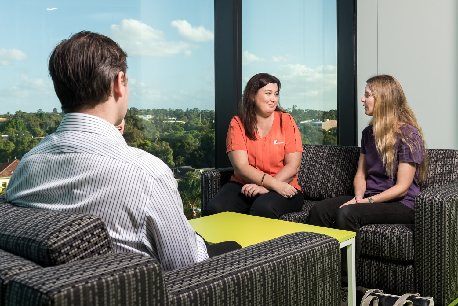 Three adults talking together in a bright seating area